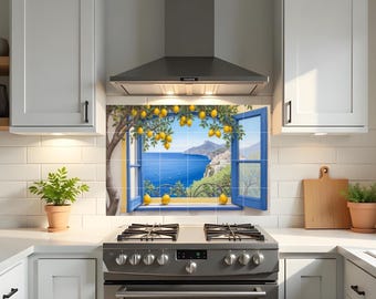 May include: A kitchen backsplash tile mural depicting a scenic coastal view. The mural features a blue window frame with a view of the sea, a lemon tree, and a coastal town. The scene is framed by white cabinets and a stainless steel range hood.