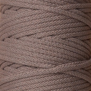 May include: A close-up of a spool of brown cotton cord. The cord is tightly wound and has a textured surface.