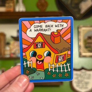 May include: A colorful sticker featuring a cartoon house with a smiling face, a red door, and a white picket fence. The text "COME BACK WITH A WARRANT!" is in a speech bubble above the house. The sticker has a blue border.