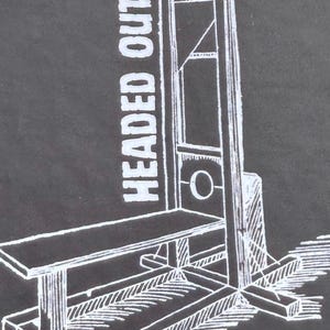 以下が含まれることがあります： 暗い灰色の背景に、ギロチンの白い線画。 「HEADED OUT」というテキストが画像の左側に縦に印刷されています。 ギロチンは、ベンチ、刃、直立フレームで描かれています。