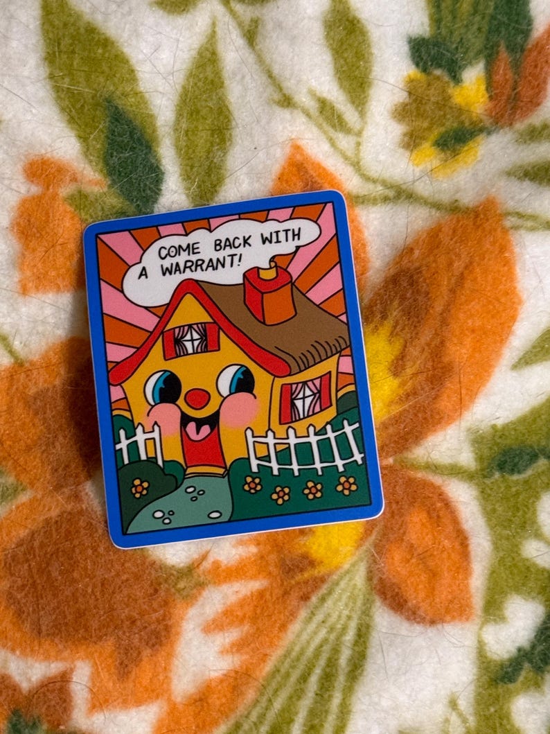 May include: A colorful sticker with a cartoon house design. The house has a smiling face, a red roof, and a white picket fence. Text on the sticker reads, "COME BACK WITH A WARRANT!" The sticker has a blue border and is set against a floral background.