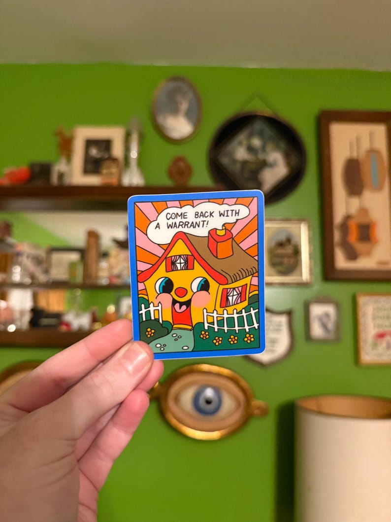 May include: A colorful sticker featuring a cartoon house with a smiling face, a red door, and a chimney. The house is yellow with a brown roof and a blue border. Text in a speech bubble reads, "COME BACK WITH A WARRANT!"