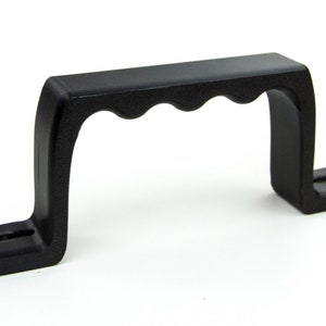 May include: Black plastic handle with a D-shaped opening and a textured grip. The handle is designed for lifting or carrying heavy objects.