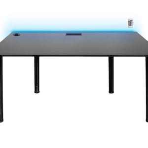 Könnte beinhalten: Schwarzer Gaming-Schreibtisch mit einer schwarzen Tischplatte und vier schwarzen Beinen. Der Schreibtisch verfügt über eine integrierte Steckdosenleiste und einen blauen LED-Lichtstreifen entlang der hinteren Kante.