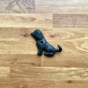 May include: Black cast iron dog hook, a decorative wall hook shaped like a dog, with two holes for hanging items.