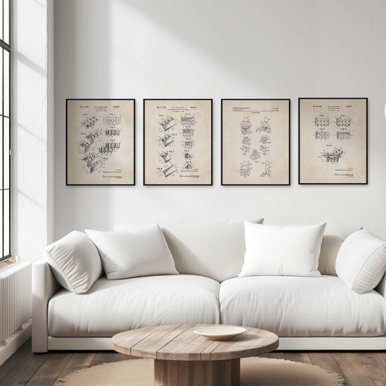 Op de afbeelding: Vier zwart-witte vintage patentprints van bouwstenen, getoond op een witte muur boven een witte bank met drie witte kussens. De prints zijn ingelijst met zwarte lijsten.