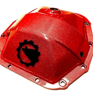 以下が含まれることがあります： 赤色の金属製ディファレンシャルカバー。テクスチャード加工が施されています。ギア型のデザインの中に黒いオオカミのシルエットがあります。周囲には複数のボルト穴があります。