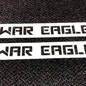May include: Two white rectangular signs with the text "WAR EAGLE" printed in black.