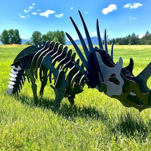 May include: A black metal dinosaur sculpture in a grassy field. The dinosaur is a skeletal model with a long neck and tail, and a large head with horns.