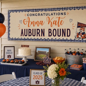May include: A rectangular banner with a navy blue gingham border, cream background, and navy and orange text reading CONGRATULATIONS Anna Kate AUBURN BOUND, featuring a cartoon tiger holding an Auburn Tigers pennant and small heart icons.