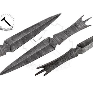Può includere: Tre lame di coltello in metallo con un motivo in acciaio damascato. Le lame sono disposte a forma di triangolo. Le lame hanno una punta appuntita e un bordo affilato.