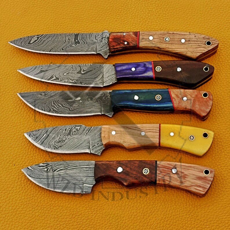 May include: Five Damascus steel hunting knives with different colored wooden handles. The knives have a unique pattern on the blades and are a great addition to any collection.