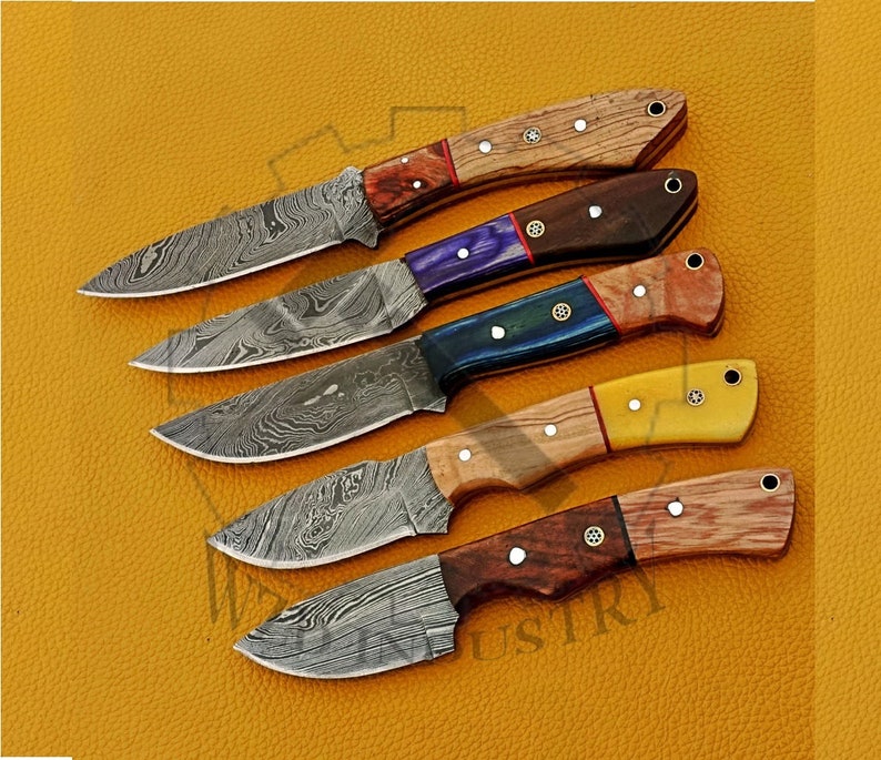 May include: Five Damascus steel knives with different colored wooden handles. The handles are made of wood with different colors and patterns. The blades are all Damascus steel with a wavy pattern.