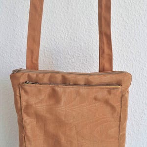 Pochette en tissu portée en bandoulière avec une poche extérieure et plusieurs compartiments  pour cartes dans la doublure