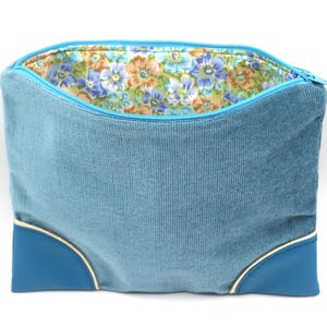 Pochette fourre tout en velours et simili bleu à fond plat, agrémenté d'un passe poil doré, doublée avec fermeture éclair.