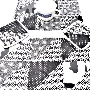 Peut inclure: Un ensemble de quatre sets de table à motifs noirs et blancs avec une tasse blanche au centre. Les sets de table présentent des motifs géométriques avec des flèches, des points et des volutes.