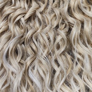May include: A bundle of blonde and light blonde synthetic dreadlocks. The dreadlocks are wavy and have a natural look.