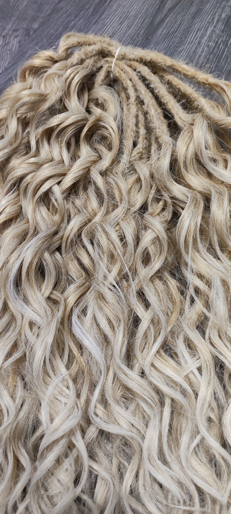 May include: A bundle of blonde and light blonde synthetic dreadlocks. The dreadlocks are wavy and have a natural look.