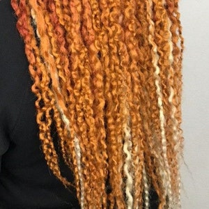 May include: A long, thick braid of hair with a mix of orange and white strands. The hair is styled in a loose, wavy braid.