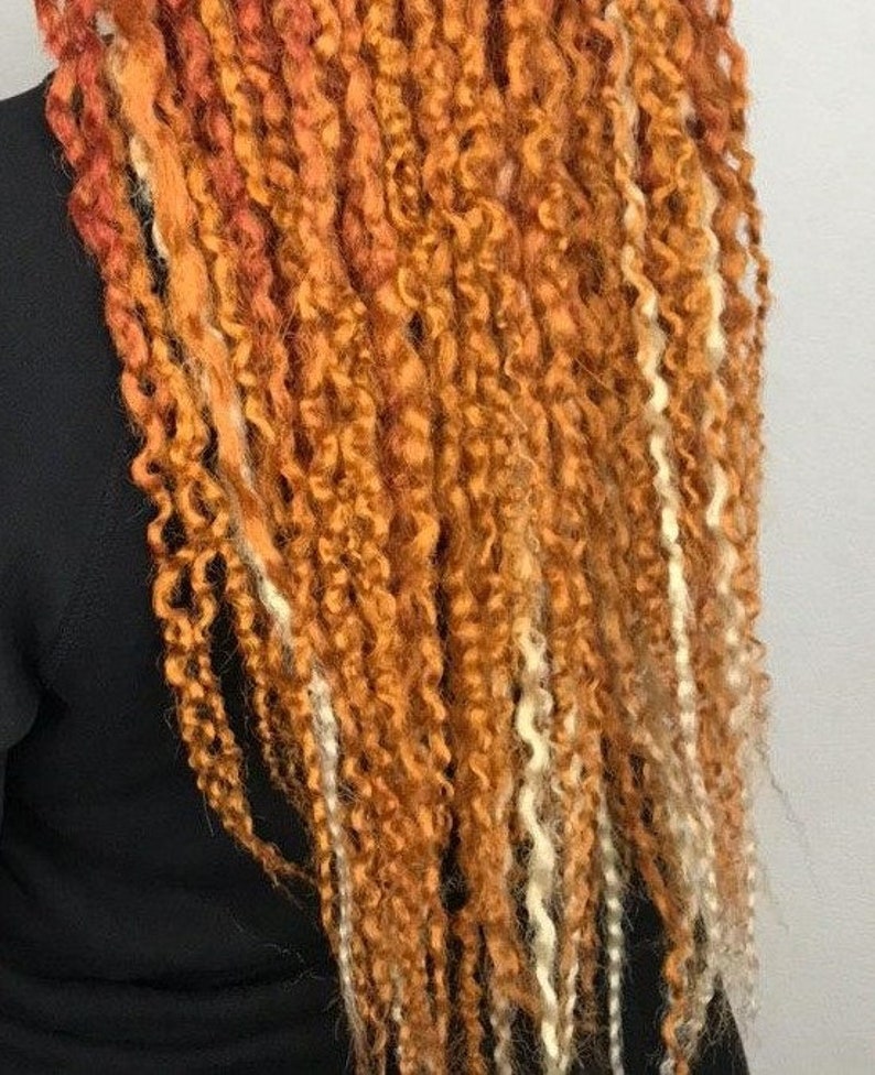 May include: A long, thick braid of hair with a mix of orange and white strands. The hair is styled in a loose, wavy braid.