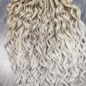 May include: A set of blonde and white ombre curly synthetic dreadlocks. The dreadlocks are made of kanekalon hair and are approximately 24 inches long.