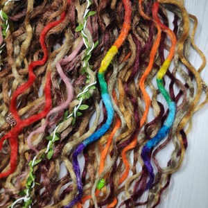 May include: A close-up of a set of colorful synthetic dreadlocks. The dreadlocks are made of brown, red, orange, yellow, blue, purple, and green yarn. The dreadlocks are arranged in a loose, flowing style.