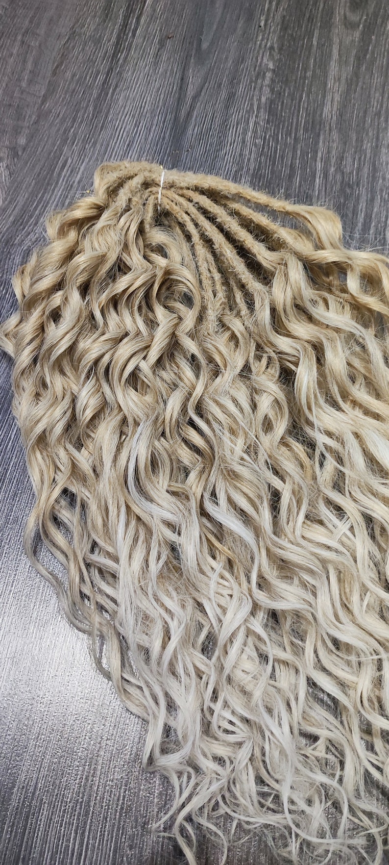 May include: A bundle of blonde and light blonde curly synthetic dreadlocks. The dreadlocks are about 20 inches long and have a wavy texture.