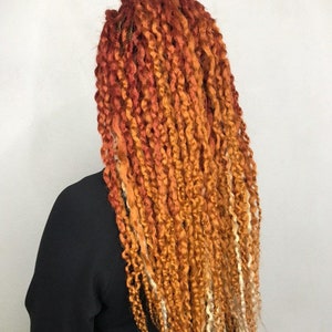 May include: Long, curly, ombre hair extensions in shades of red, orange, and blonde.