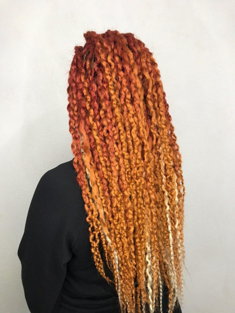 May include: Long, curly, ombre hair extensions in shades of red, orange, and blonde.