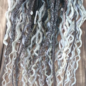 May include: A set of long, curly, synthetic dreadlocks in shades of black, gray, and white. The dreadlocks are arranged in a loose, flowing style.