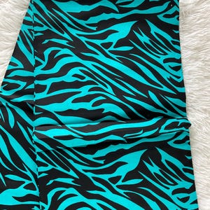 May include: A turquoise and black fabric with a zebra print pattern.