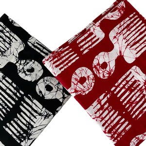 May include: Two folded fabric squares, one black and one red, each with a white comb-like pattern. The black fabric has a white, marbled design, while the red fabric has a similar pattern. The fabric is likely cotton or a similar material.