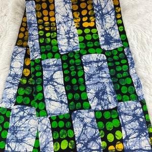 May include: A fabric with a repeating pattern of blue, green, and yellow circles on a black background. The circles are arranged in rows and columns, and the fabric has a white, blue, and black tie-dye effect.