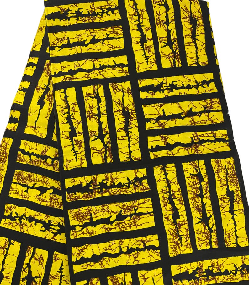 Puede incluir: Una tela doblada con un patr&oacute;n geom&eacute;trico audaz. El dise&ntilde;o presenta una cuadr&iacute;cula de rect&aacute;ngulos y l&iacute;neas negras sobre un fondo amarillo brillante. Detalles marrones de forma org&aacute;nica llenan los rect&aacute;ngulos.