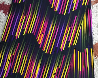 May include: Black fabric with a colourful striped pattern. The stripes are yellow, pink, purple, and green. The fabric has a subtle sheen.