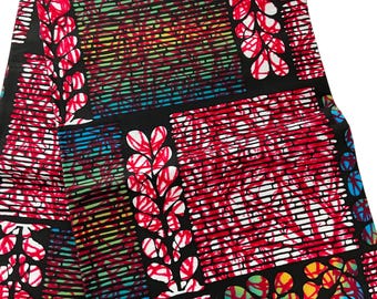 May include: A folded piece of fabric with a vibrant, geometric pattern. The design features red, white, blue, and yellow accents on a black background. The fabric has a repeating pattern of leaf-like shapes and horizontal lines.