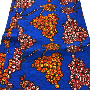 May include: Vibrant blue fabric with a repeating pattern of orange and red clusters resembling grapes, with green and orange leaves. The design is set against a blue background with subtle wave-like lines, creating a visually striking textile.