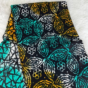 May include: Black fabric with a white, yellow, and teal floral pattern. The fabric has a batik style design.