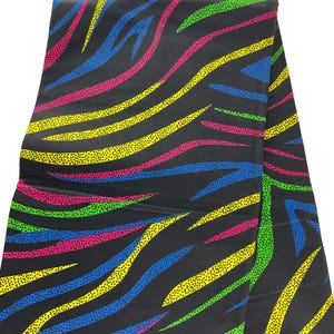 May include: Black fabric with a colorful zebra print. The print features yellow, blue, green, and pink stripes with small yellow dots on a black background.