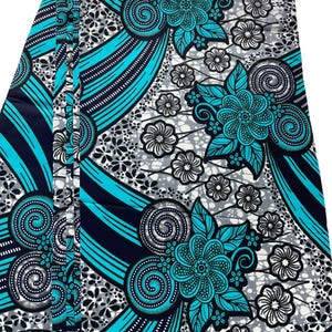 May include: A folded fabric with a vibrant floral pattern. The design features large turquoise flowers with intricate details, set against a backdrop of gray and white floral motifs. Bold turquoise stripes and navy blue accents create a striking contrast.