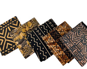 May include: Five folded pieces of fabric arranged in a row, each featuring distinct black and gold or brown geometric patterns. The designs include repeating triangles, dots, chevron lines, and abstract shapes printed on dark textile surfaces.