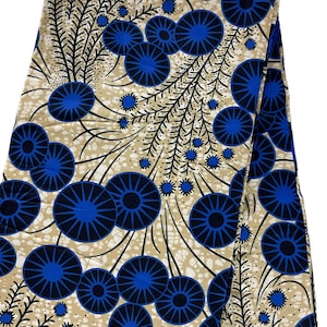 Pode incluir: Tecido bege com um padrão repetido de círculos azuis e pretos com um design de estrela. O tecido tem um fundo branco salpicado.