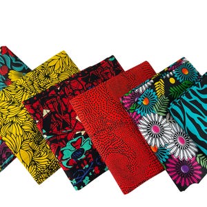 May include: Six folded pieces of fabric arranged in a row, featuring diverse patterns including yellow floral prints, red and black geometric designs, a solid red dotted texture, a multi-colored floral motif, and a black and turquoise zebra print.