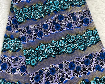 May include: A blue and purple fabric with a repeating pattern of small circles and flowers. The fabric has a gold glitter finish.