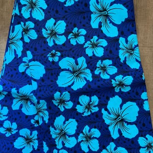 May include: Blue fabric with a repeating pattern of light blue hibiscus flowers with black centers on a dark blue background.