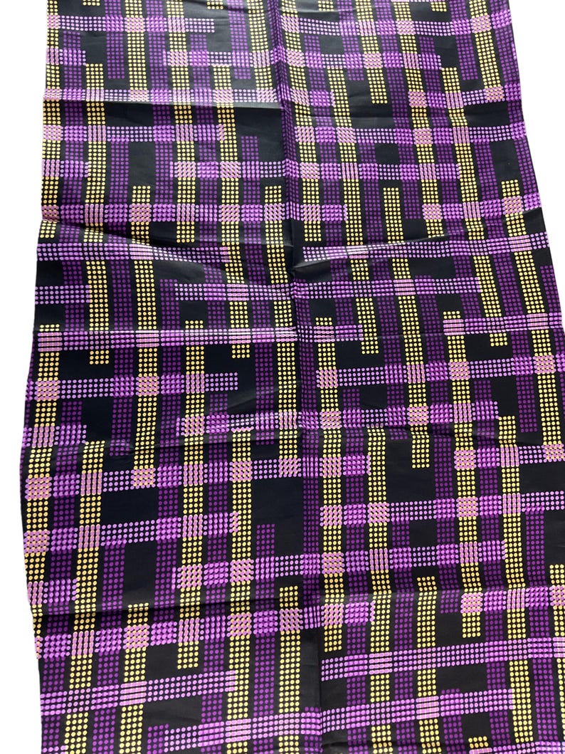 May include: A fabric with a geometric pattern. The design features a grid of intersecting lines in purple, yellow, and pink dots against a black background. The fabric has a shiny appearance and a repeating pattern.