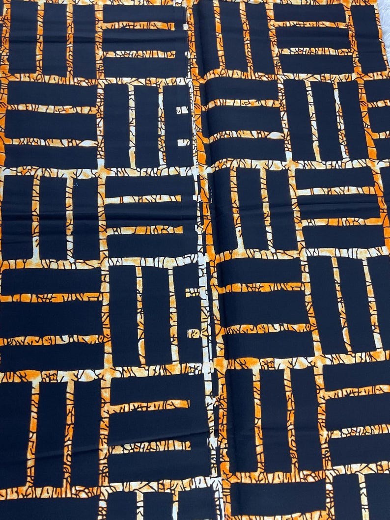 Puede incluir: Primer plano de una tela con un patr&oacute;n geom&eacute;trico. El dise&ntilde;o presenta rect&aacute;ngulos azul marino oscuro delineados en naranja, con una red de l&iacute;neas naranjas y espacios blancos. La tela tiene una apariencia texturizada.