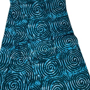 May include: A piece of fabric featuring a repeating pattern of dark navy blue spiral shapes set against a vibrant turquoise background. The design consists of thick, hand-drawn style circular lines that create a dense, continuous graphic texture.