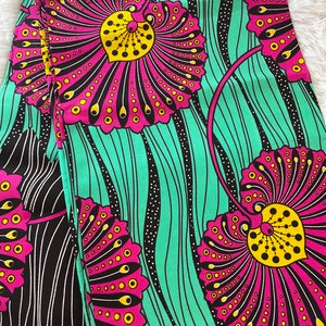 May include: A fabric with a repeating pattern of pink and yellow flowers on a turquoise background. The flowers have black outlines and are surrounded by black wavy lines.