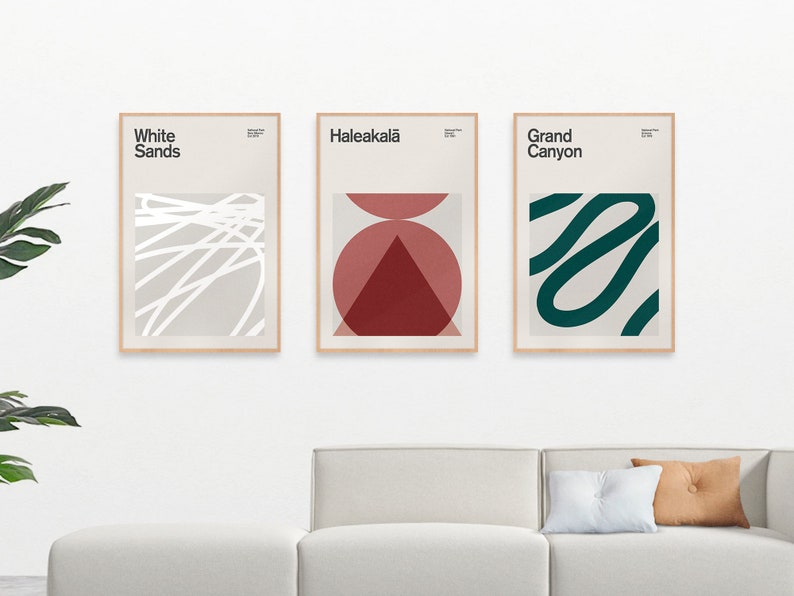 May include: Three framed abstract art prints with minimalist designs. The left print features white lines on a light gray background with the text "White Sands". The middle print features a red and pink geometric design with the text "Haleakala". The right print features a green squiggly line on a light gray background with the text "Grand Canyon".